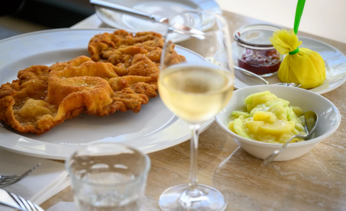 Ein gedeckter Tisch mit einem Teller Wiener Schnitzel und einem Glas Wein im Das Einstein-Mommseneck.