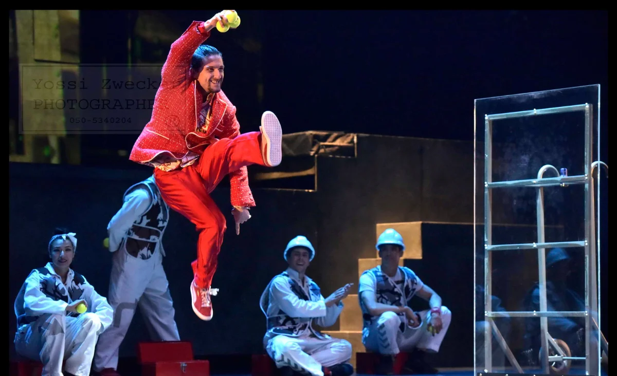 Ein Mann in Rot springt in die Luft, während Zuschauer fasziniert zuschauen. Cirque Éloize Performance.