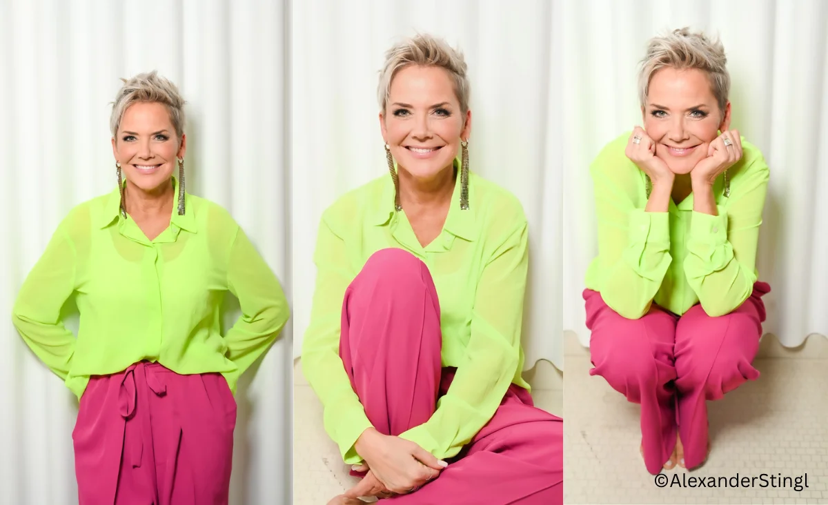 Inka Bause in auffälligen pinken Hosen und einem grünen Oberteil posiert lächelnd.