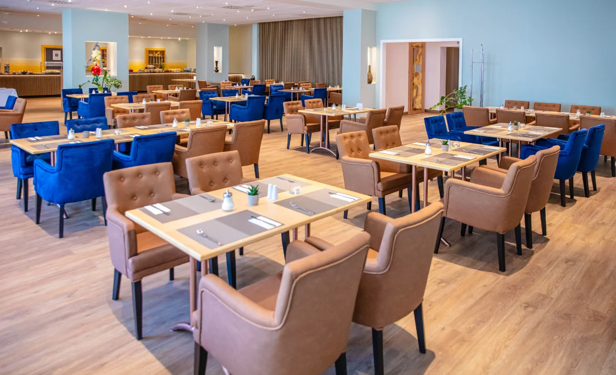 Innenansicht eines Restaurants mit Tischen und Stühlen, die eine gemütliche Umgebung bieten.