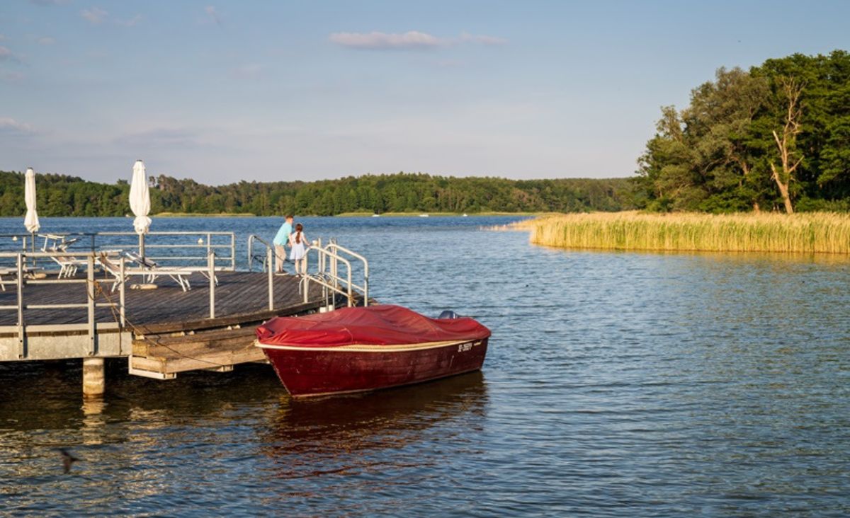 Ein rotes Boot liegt am Dock eines Sees.