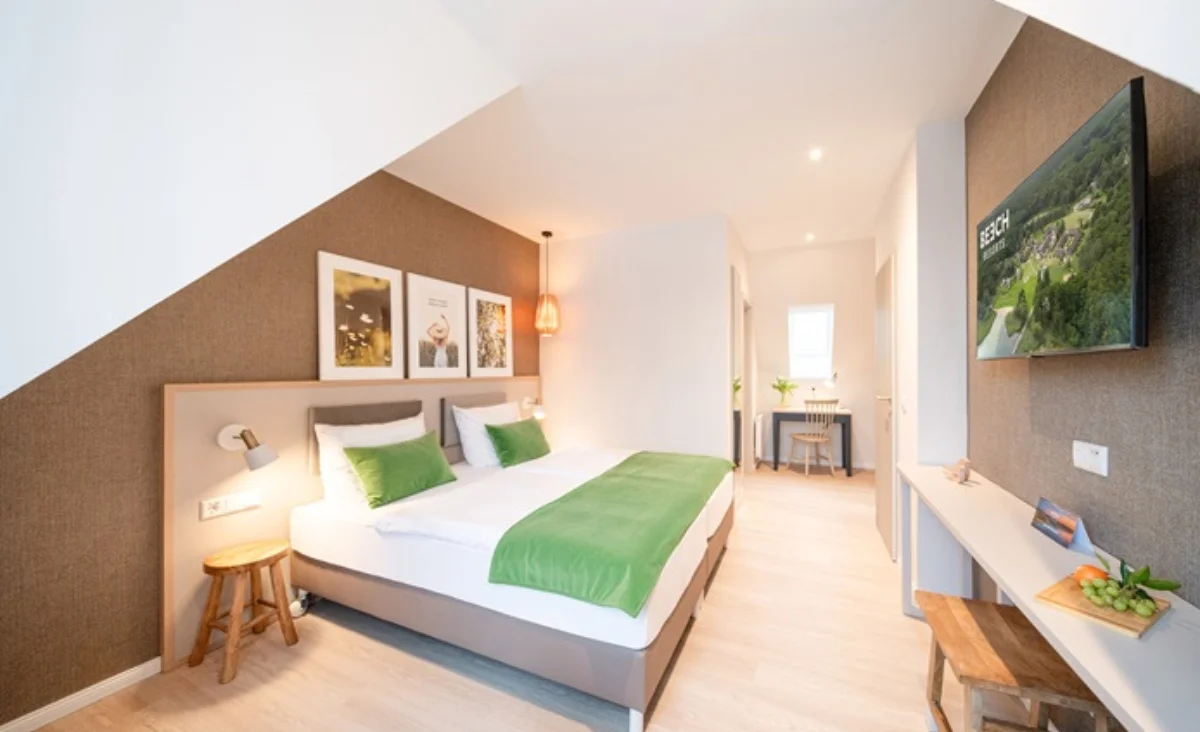 Hotelzimmer mit einem Bett, Schreibtisch und Fernseher, gemütlich und modern eingerichtet.