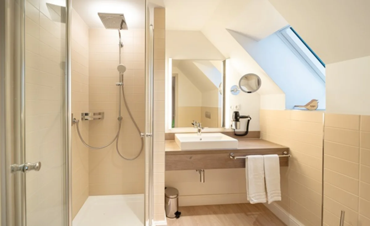 Badezimmer mit Dusche, Waschbecken und Toilette, ausgestattet und sauber.