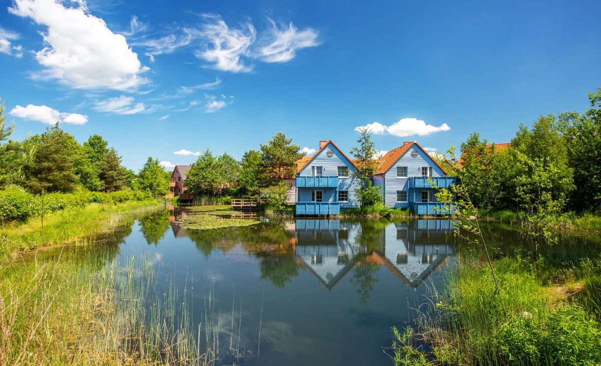 Ein ruhiger See mit Häusern im Hintergrund, ideal für einen Familienurlaub an der Mecklenburgischen Seenplatte.