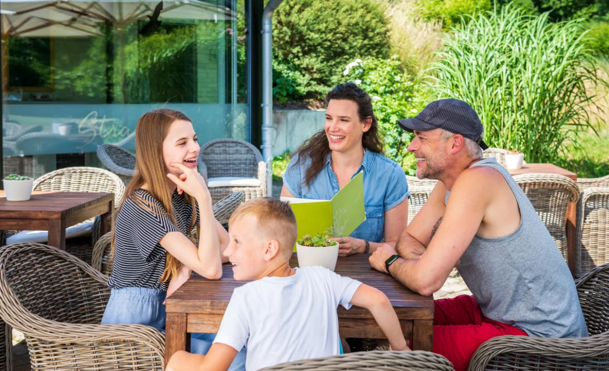 Eine Familie versammelt sich um einen Tisch im Freien, um Zeit miteinander zu verbringen.