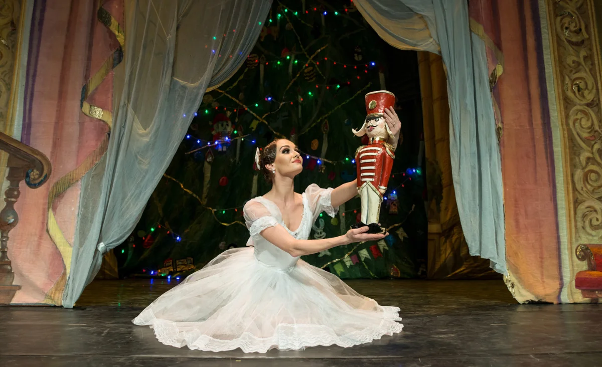 Im Stage Theater Berlin steht eine Frau in einem weißen Ballettkleid, mit einem Nussknacker in der Hand.
