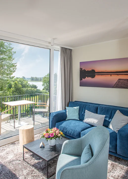 Gemütliches Wohnzimmer mit blauer Couch und Wasserblick im 5 Sterne Resort Müritz.