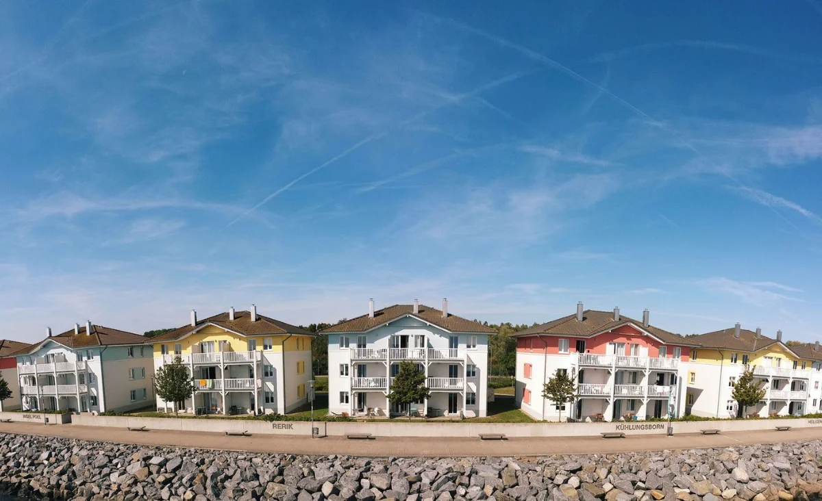 Eine Reihe von Häusern am Strand mit einer Bank, ideal für einen Familienurlaub an der Ostsee.