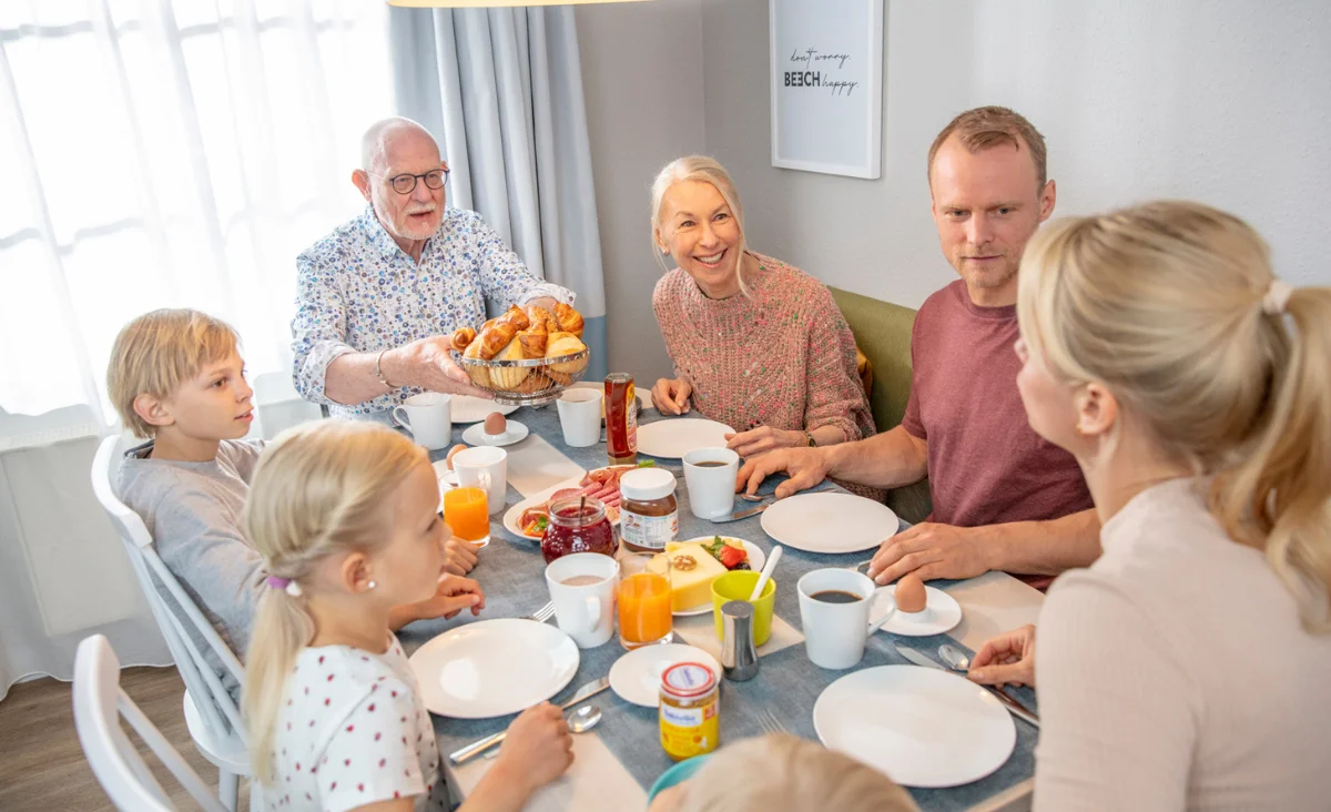 Eine Familie genießt ein Frühstück am Tisch während ihres Urlaubs an der Mecklenburgischen Seenplatte.