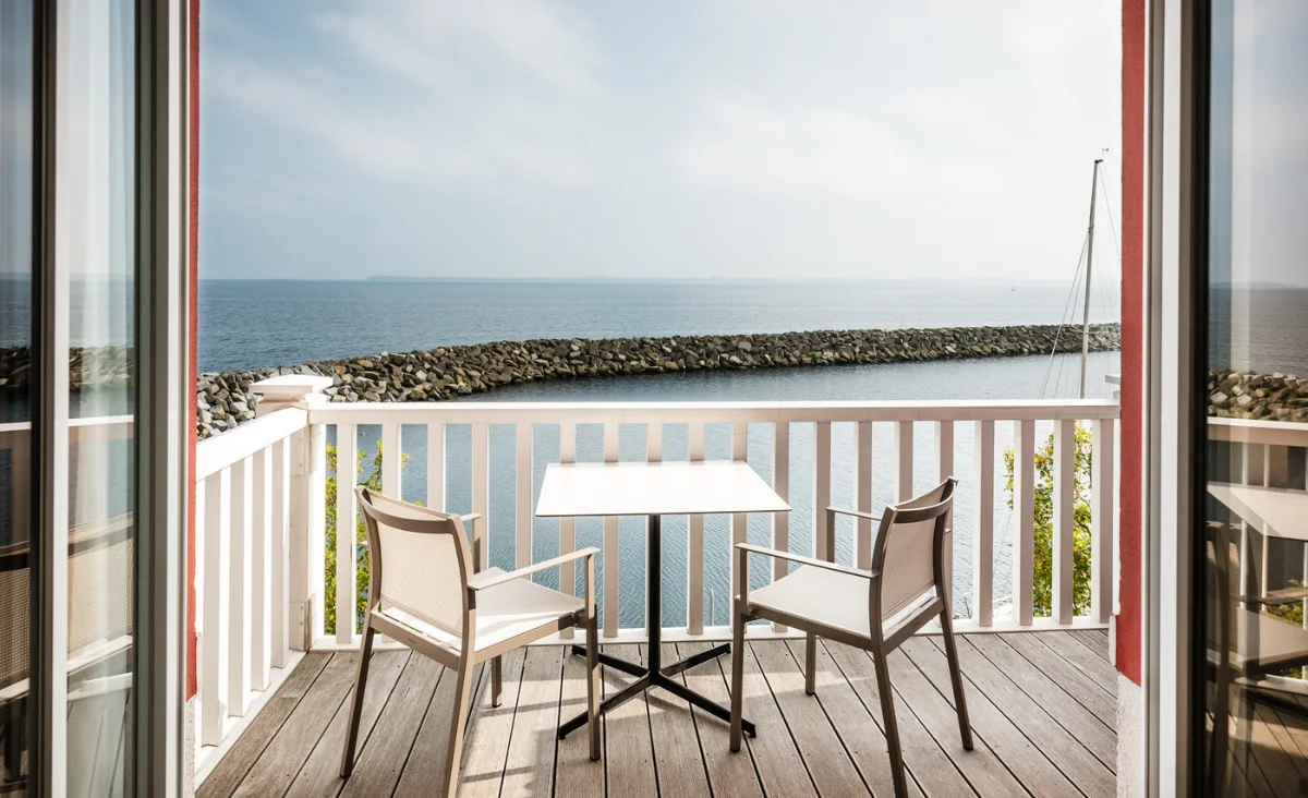 Ein Balkon mit Tisch und Stühlen, der einen Blick auf das Meer bietet. Ideal für einen Familienurlaub an der Ostsee.