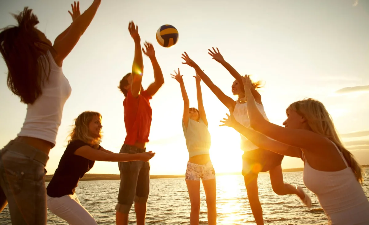 Eine Gruppe von Menschen spielt Volleyball am Strand während ihres Familienurlaubs an der Ostsee