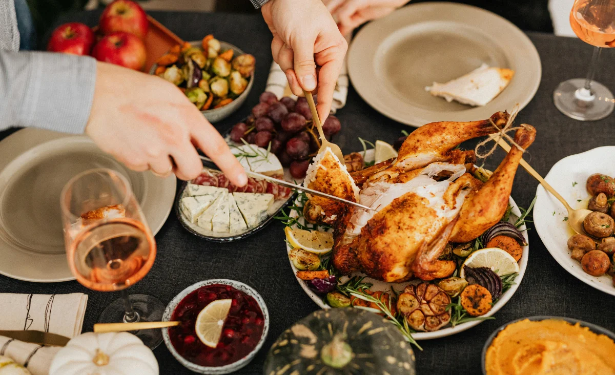 Ein festlich gedeckter Tisch mit einer Weihnachtsgans, buntem Gemüse und einer Flasche Wein, zubereitet von der Kiezküchen.