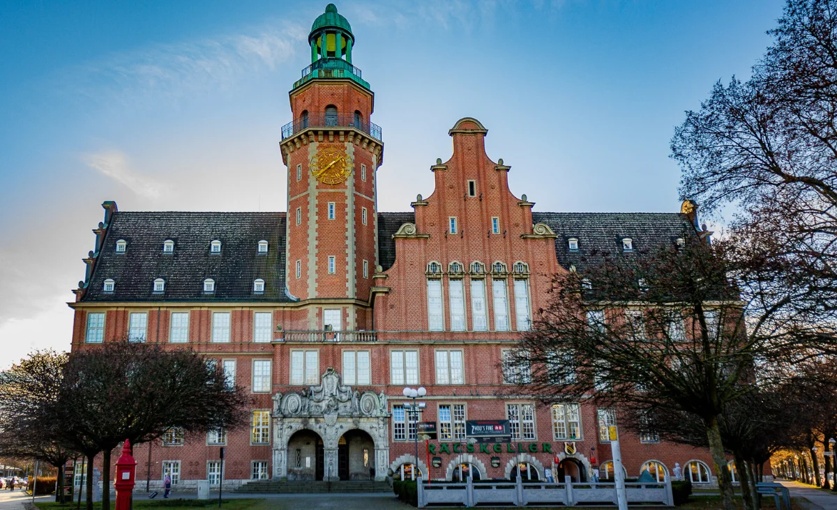 Großes Gebäude mit einem Uhrturm, das Zhou's Fine im Ratskeller Reinickendorf darstellt.