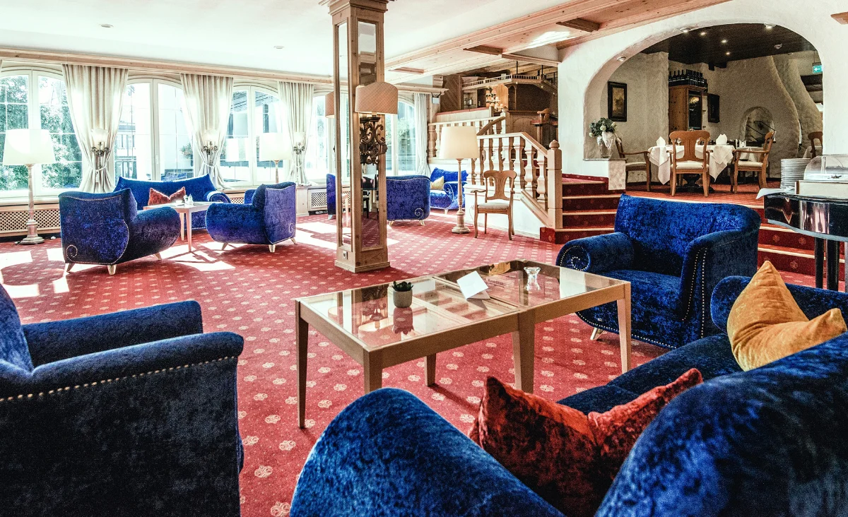 Hotel-Lobby im Mühl Vital Resort mit blauen Samtcouches und einer eleganten Treppe.
