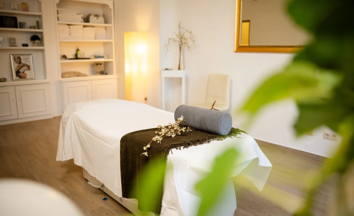 Massagezimmer im Mühl Vital Resort in Bad Lauterberg mit weißen Laken und einer Pflanze im Hintergrund.