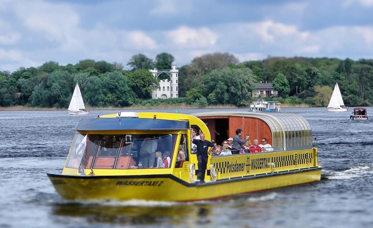 Wassertaxi in Potsdam: Gelbes Boot mit mehreren Personen, das über das Wasser gleitet.