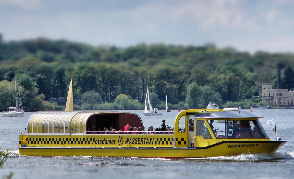Potsdamer Wassertaxi in Gelb und Schwarz, das auf dem Wasser gleitet, umgeben von urbaner Umgebung.