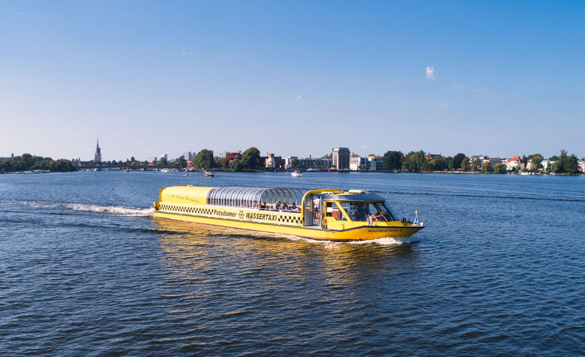 Gelb-schwarzes Wassertaxi gleitet über das Wasser eines Flusses in Potsdam.