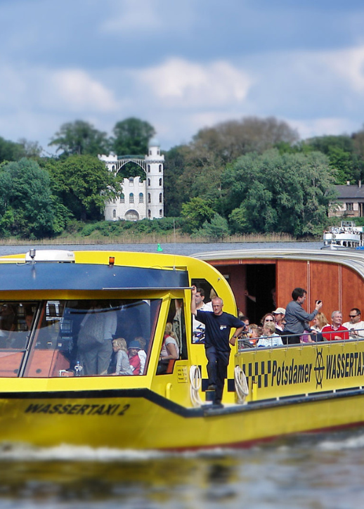 Wassertaxi in Potsdam, gelb und schwarz, mit mehreren Personen, die auf dem Boot sitzen gebucht mit dem "Potsdamer Wassertaxi Einzelticket"