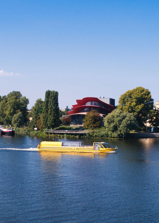 Wassertaxi auf dem Potsdamer Gewässer, umgeben von urbaner Landschaft und grünen Ufern.