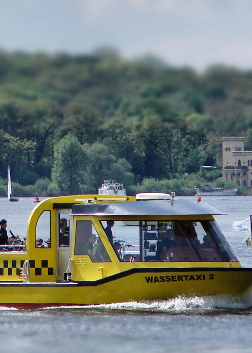 Potsdamer Wassertaxi in Gelb und Schwarz, das auf dem Wasser gleitet, umgeben von urbaner Umgebung.