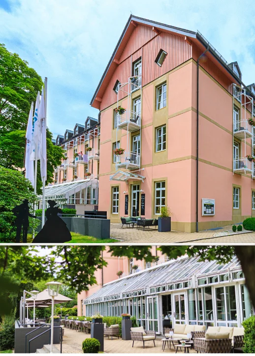 Mehrstöckiges Wellnesshotel in Bad Steben mit rosa Fassade, mehreren Balkonen und einer großen verglasten Terrasse mit Außenbestuhlung in einem grünen Umfeld