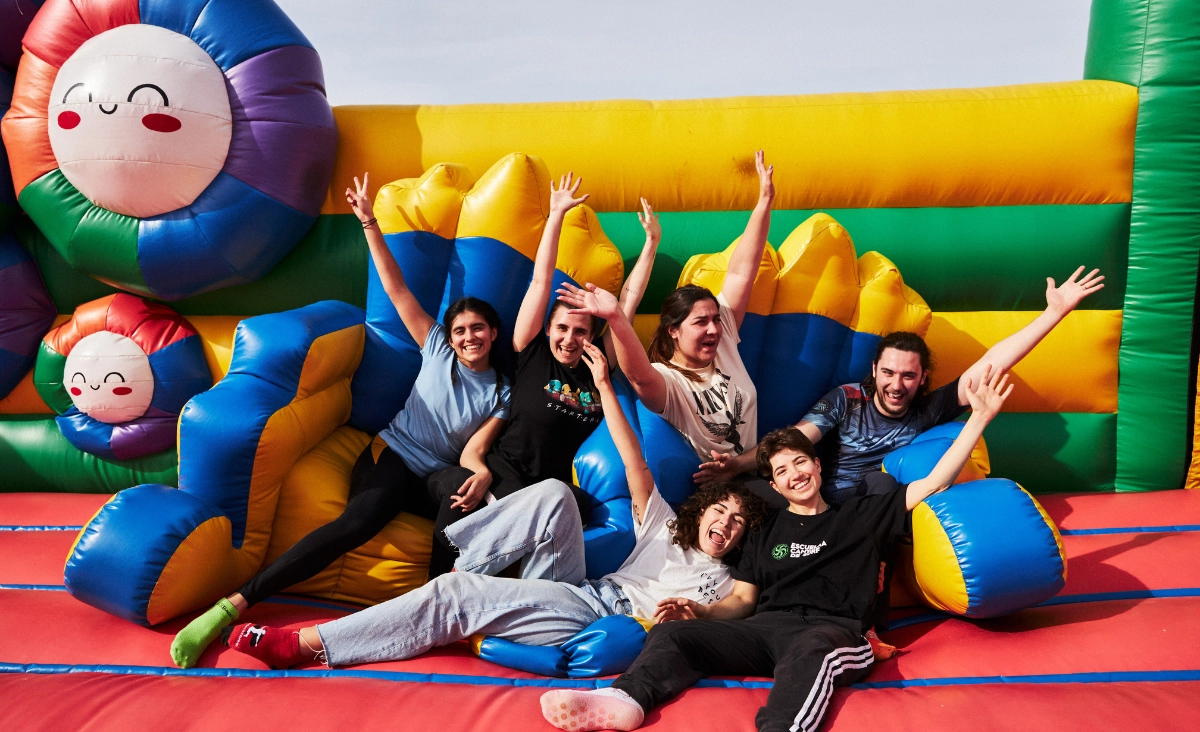 Gruppe von Menschen sitzt und liegt lachend auf einer bunten aufblasbaren Spielfläche in einem Fun Box Park