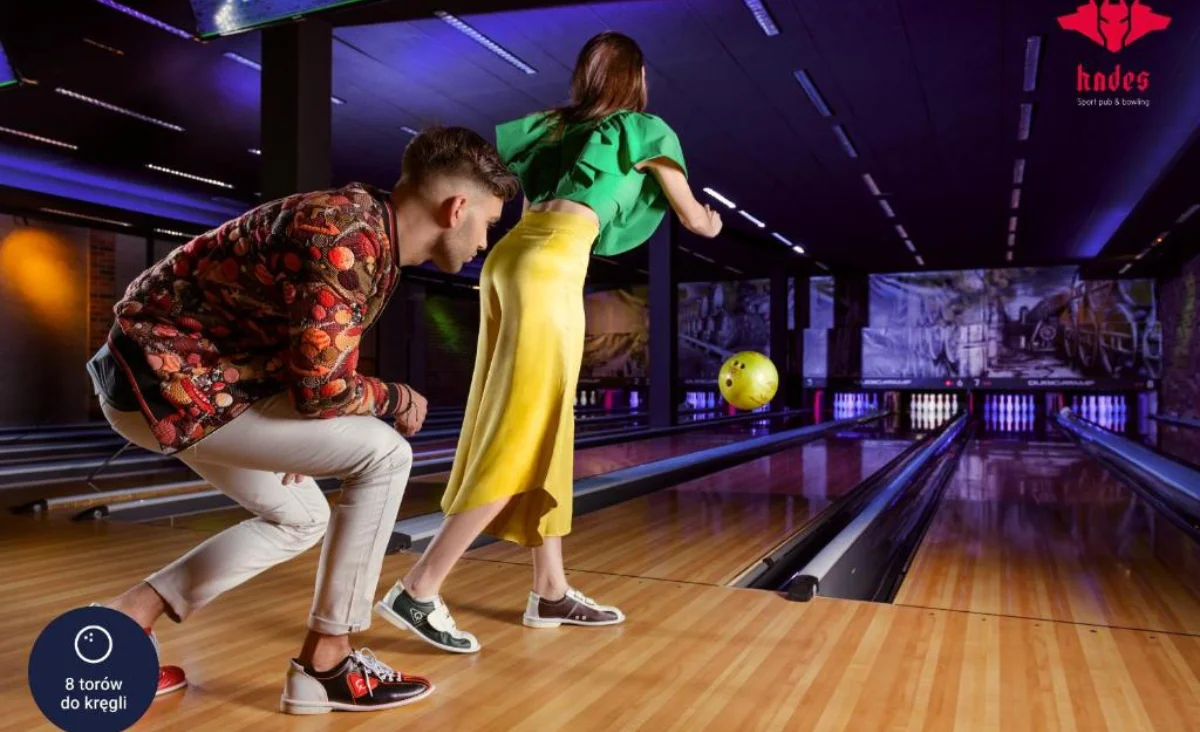 Ein Mann und eine Frau spielen Bowling auf einer Bahn im Grape Town Hotel in Zielona Góra.