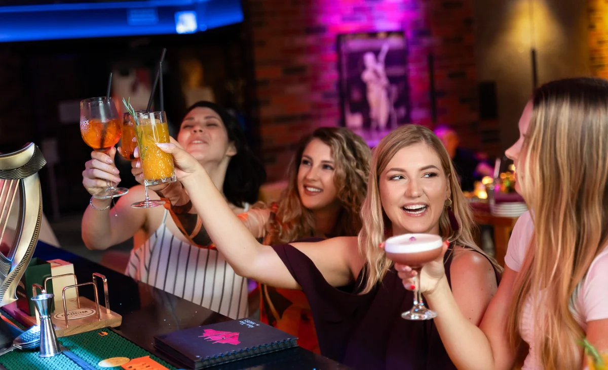 An der Bar des Grape Town Hotels in Zielona Góra stoßen drei Frauen fröhlich an.