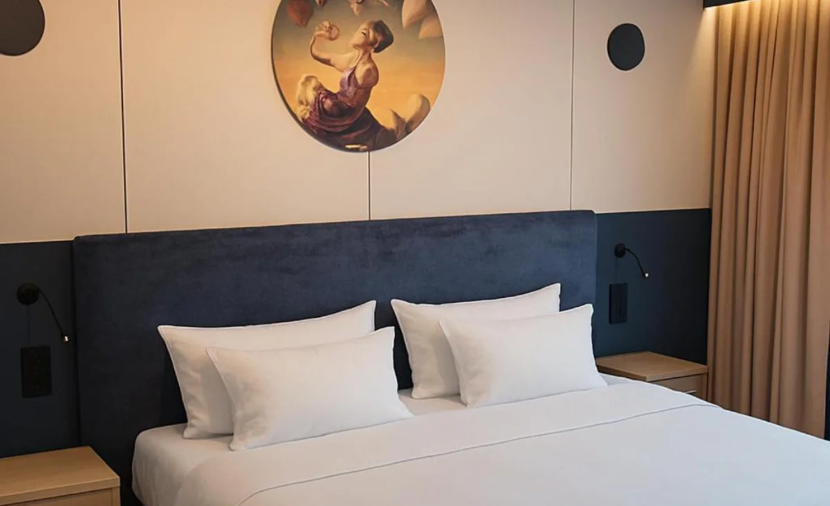 Gemütliches Hotelzimmer im Grape Town Hotel Zielona Góra, ausgestattet mit einem Bett und einem Wandgemälde.