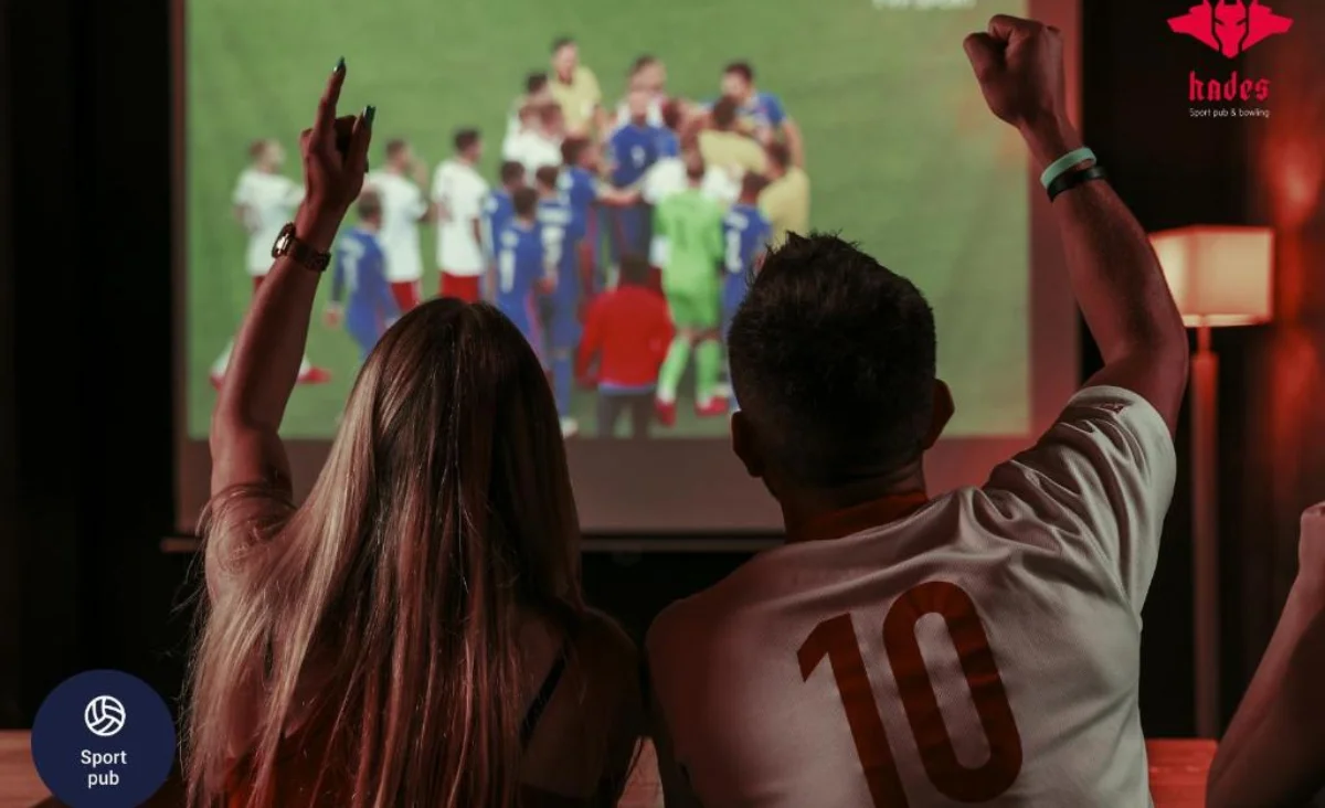 Zwei Personen schauen ein Fußballspiel im Grape Town Hotel in Zielona Góra im Fernsehen.