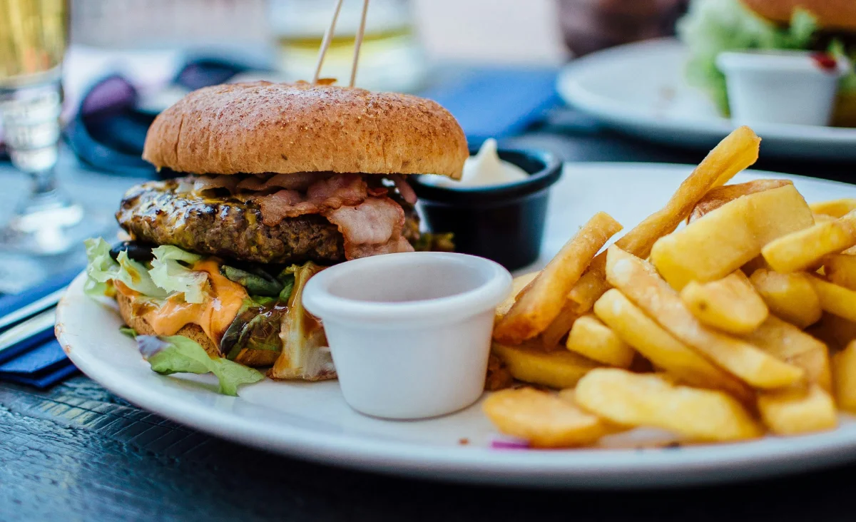 Burger mit Salat, Käse und Speck auf einem Teller mit Pommes beim Street Food Festival Zehlendorf