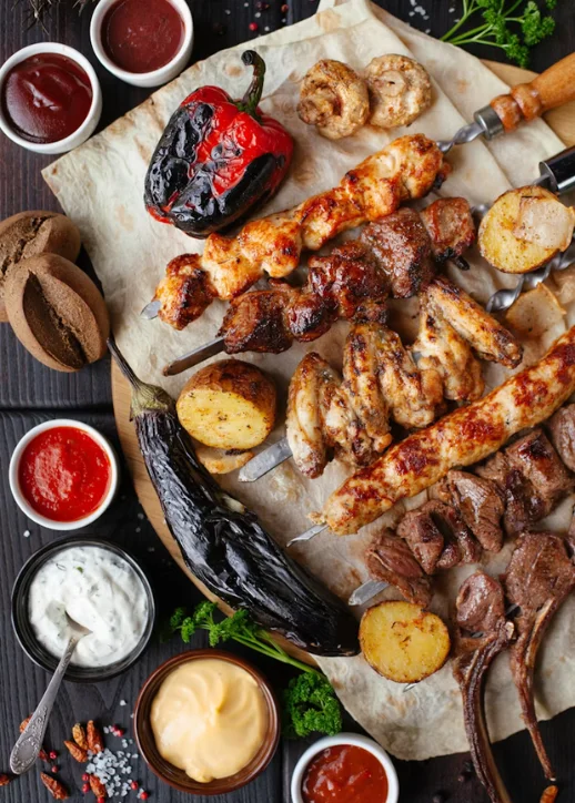 Street Food Festival Zehlendorf: Gegrillte Fleischspieße mit gegrilltem Gemüse und verschiedenen Dips auf Backpapier angerichtet