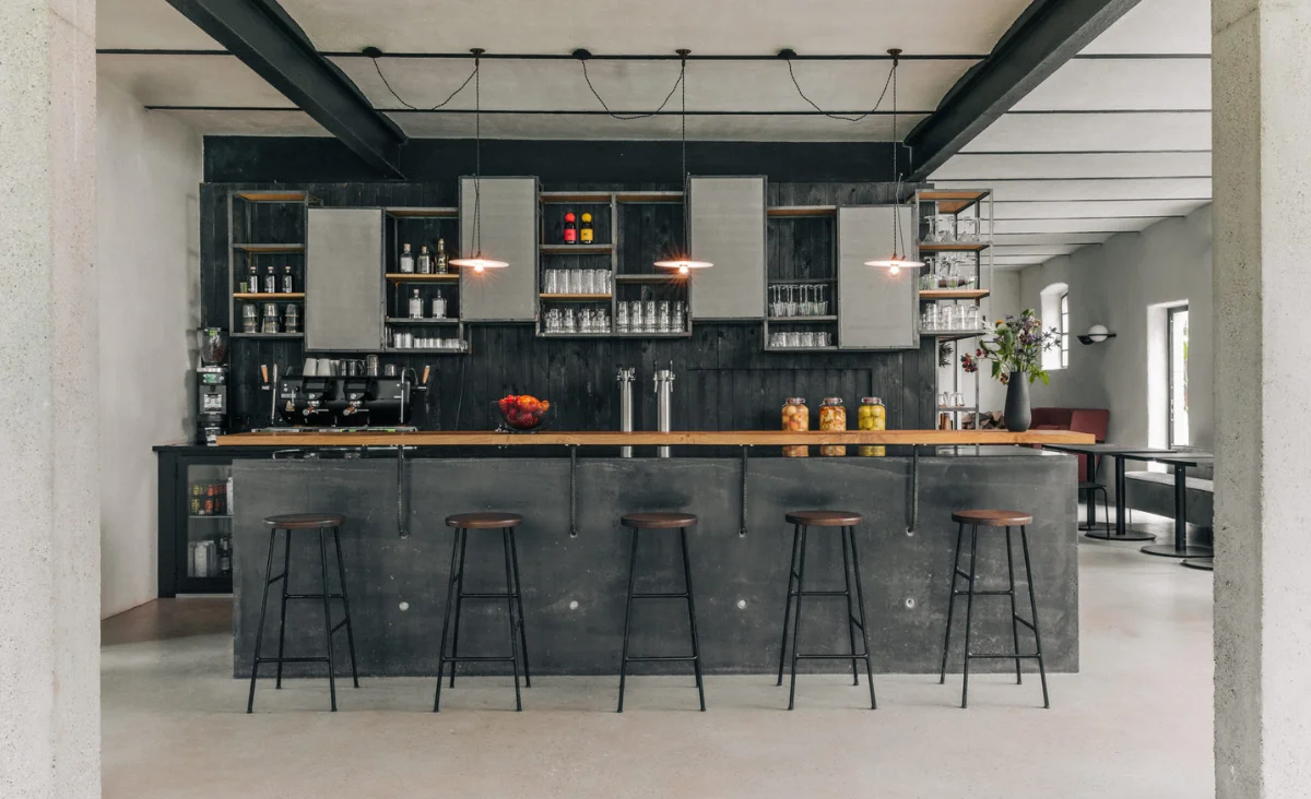 Moderne Bar mit fünf hohen Hockern, dunklem Tresen und Regalen mit Gläsern und Flaschen im Astraea Eco Resort