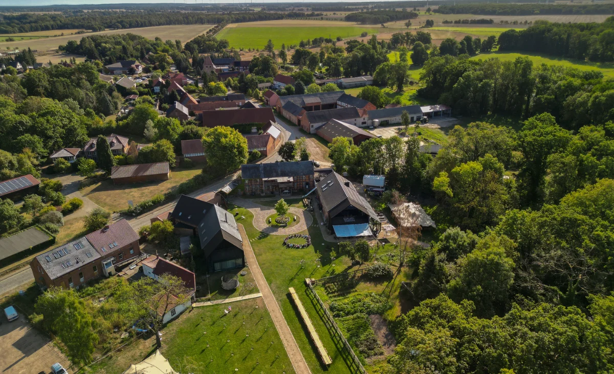 Luftaufnahme des Astraea Eco Resort mit mehreren Gebäuden, Wegen und umgeben von Feldern und Waldflächen