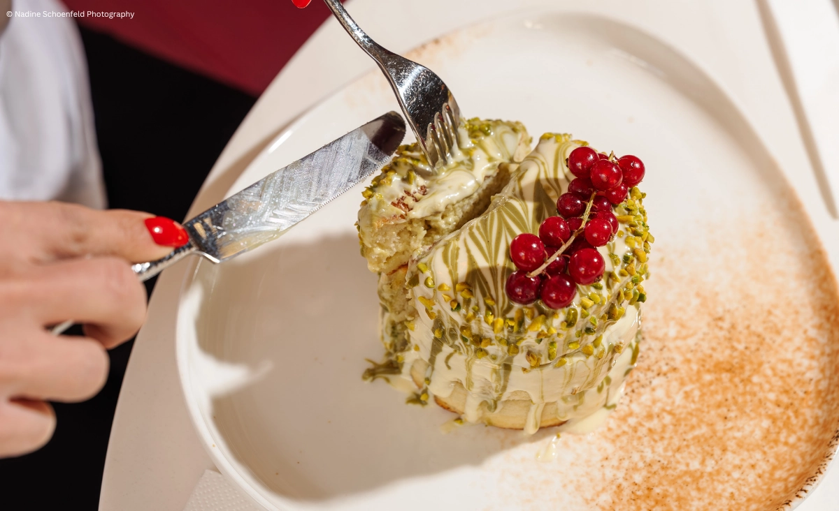 Eine Person verwendet ein Messer und eine Gabel, um einen Kuchen zu schneiden.