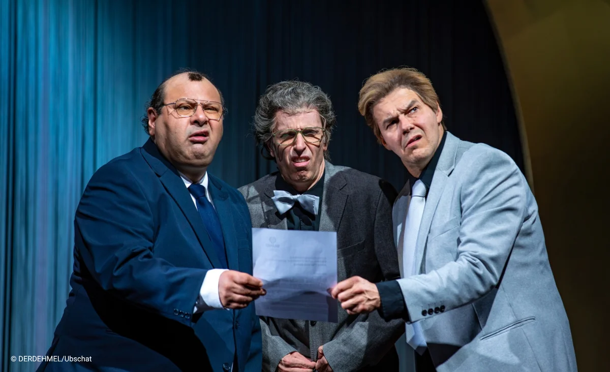 Drei Schauspieler des Putsch Theaterstückes im Schlosspartk Theater in Anzügen stehen eng beieinander